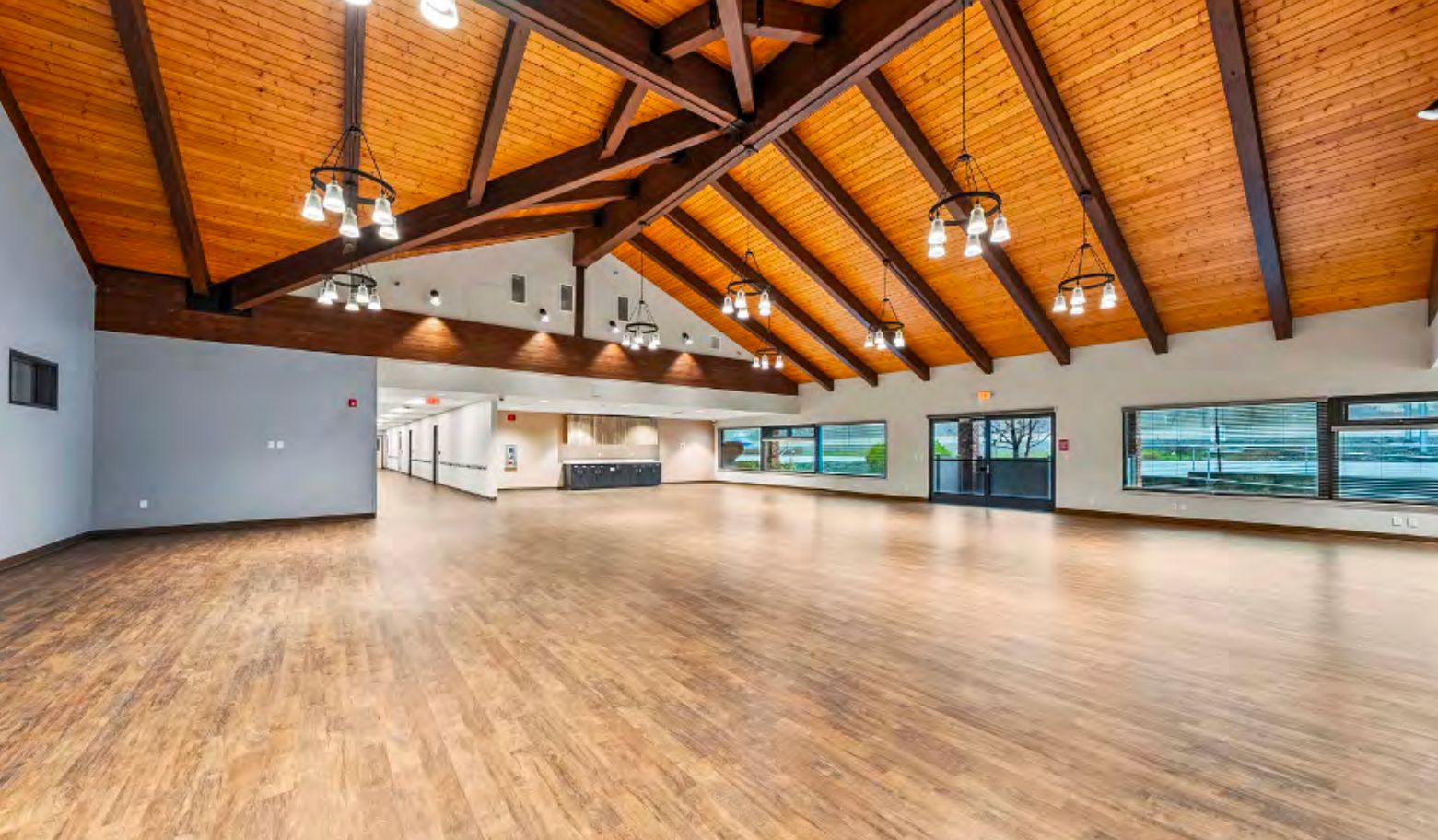 The great hall at 2166 with a vaulted wood ceiling, iron chandeliers, and an open wood floor.